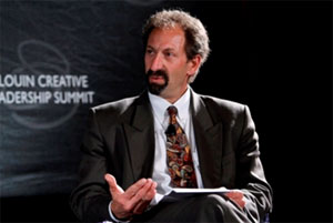 A man against a black background gesturing during a panel discussion.