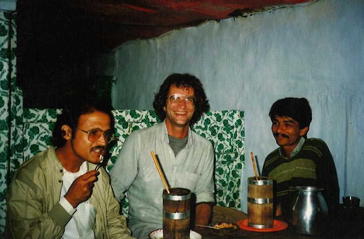 Three men siting around a table smiling.