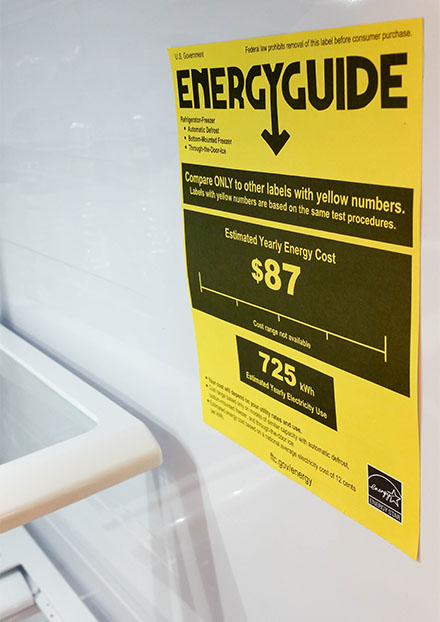 the front of a refrigerator with a yellow paper showing the Energy Guide rating, or the energy efficiency of the appliance.